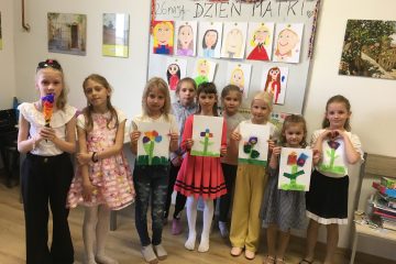 grupa dziewczynek, każda z nich trzyma namalowany obrazek
