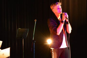 zdjęcie śpiewajacego na scenie wokalisty