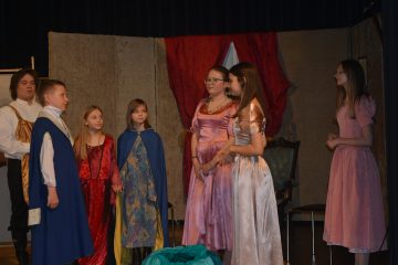 Dzieci grające spektakl teatralny, ubrane w stroje królów i księżniczek