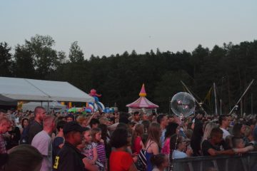 Tłum ludzi podczas Poniatowianek, ludzie trzymają balony, a w tle wesołe miasteczko