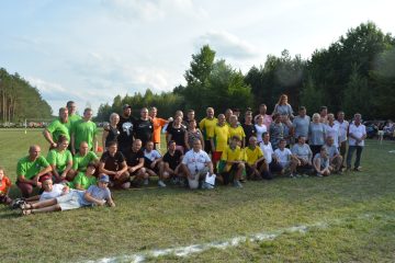 zdjęcie ludzi w grupie, ubrani w szare, czarne, żółte, zielone stroje, ludzie na boisku sportowym