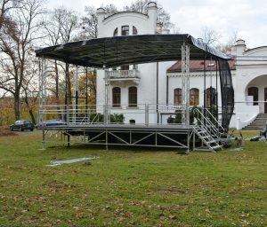 Scena mobilna stojąca w parku, w tle drzewa i Do Muzyki w Kraczewicach