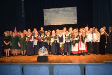 zdjęcie przedstawia zespół śpiewaczy na scenie oraz gości świętujący jubileusz