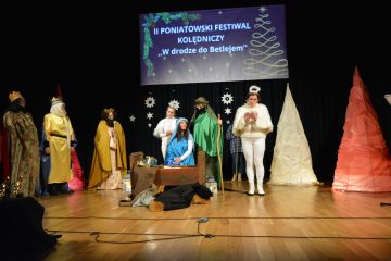 zdjęcie przedstawia scenę, na której stoją artyści przedstawiający Jasełka, na scenie stoi bała choinka