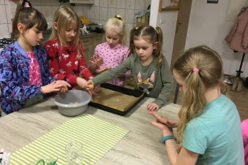 zdjęcie przedstawia 5 dziewczynek, które wspólnie przy stole robią ciastka