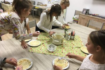 grafika przedstawia dzieci przy stole, dzieci przygotowują jedzenie